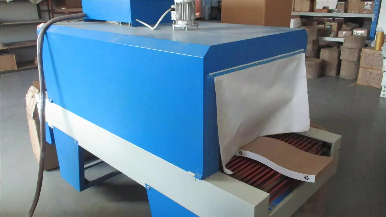 Heat-shrink tunnel giving a corrugated cat scratcher a tight, retail-ready wrap as it leaves the line.