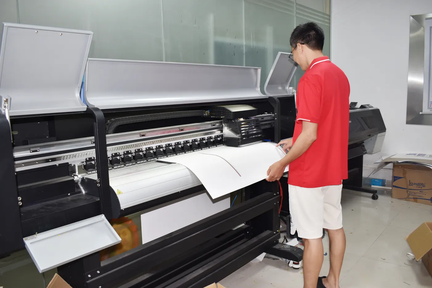 An operator pulling a proof sheet from the wide-format printer before scratcher artwork is approved.
