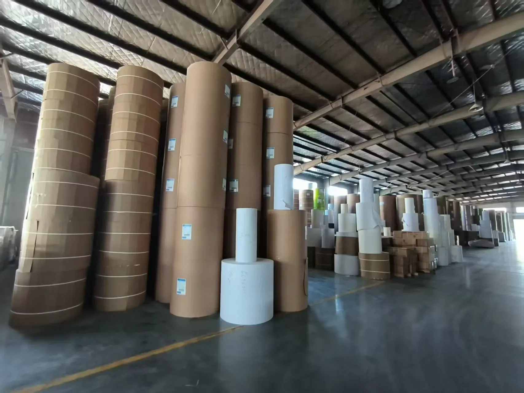 Kraft and white paper rolls in covered storage, kept dry for a clean face on the next scratcher run.